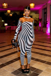 Woman in a zebra-striped outfit  by Gsuwoo standing in a stylishly decorated room with pink lighting.